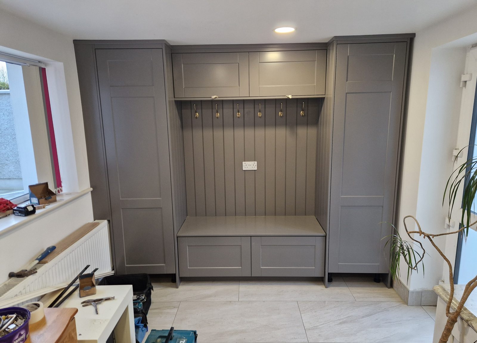 Grey mudroom with tall locker units, bench and coat hooks